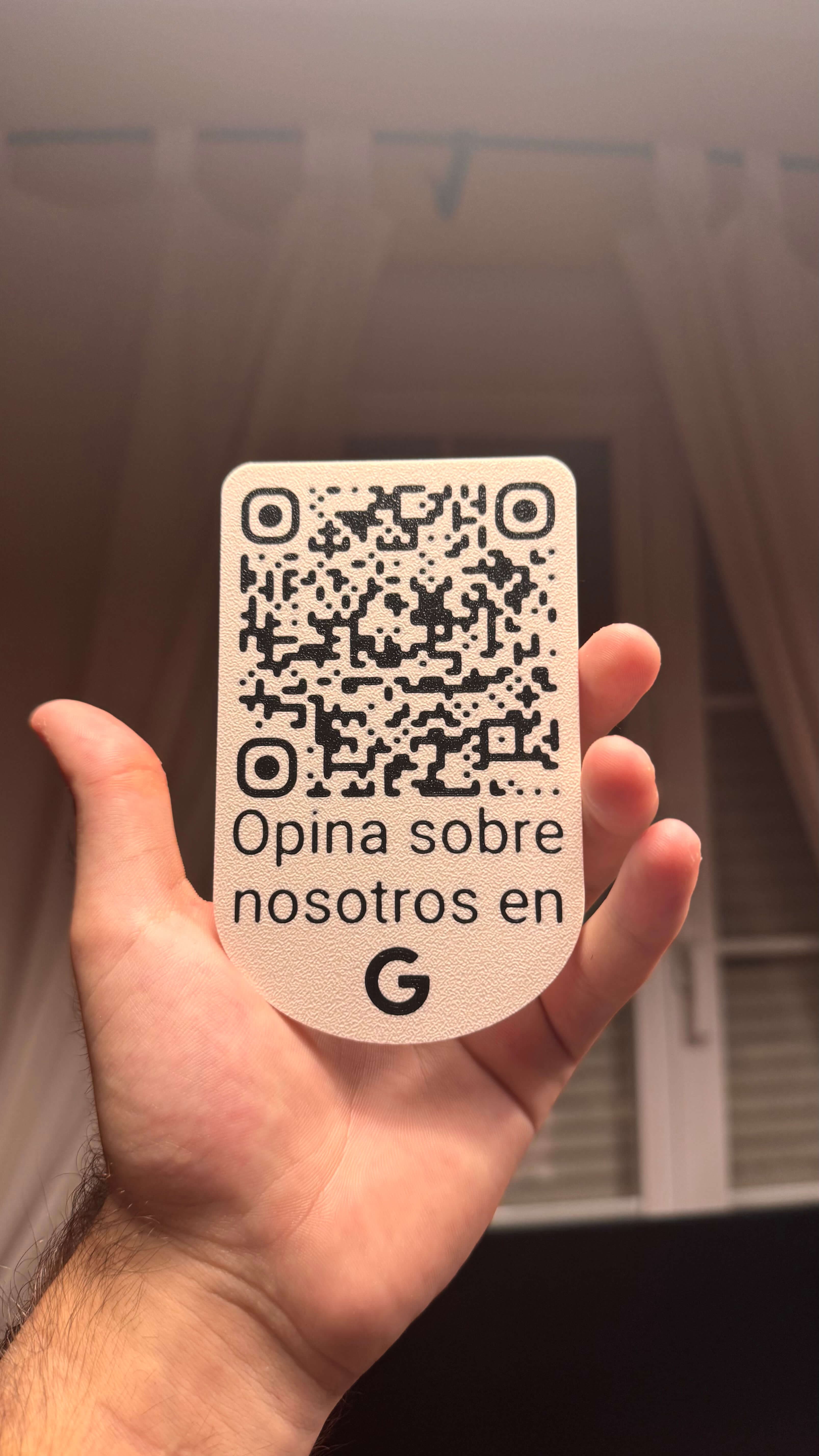 Placa QR de reseñas de Google sujetada con la mano en el interior de un negocio