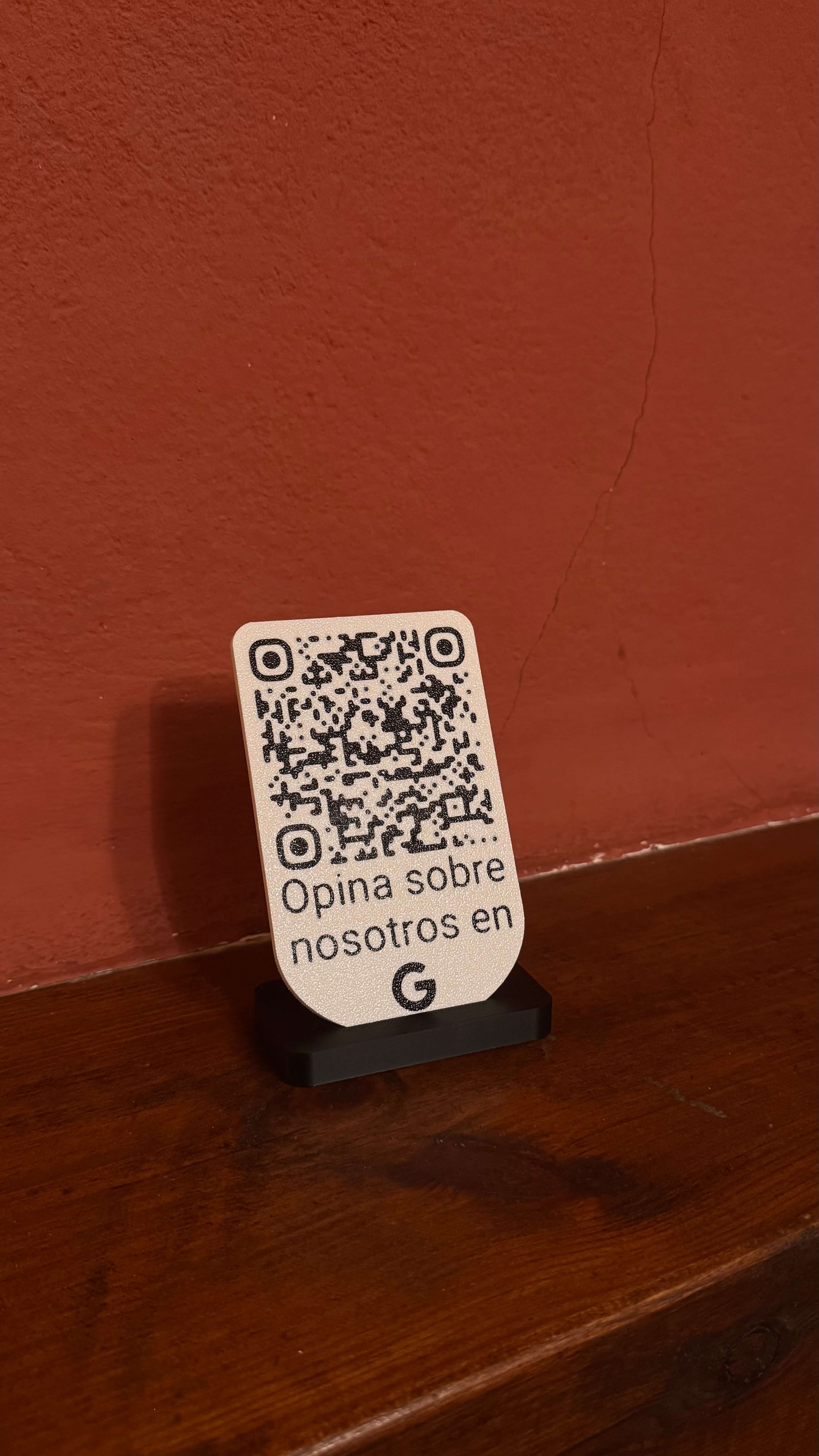 Placa QR de reseñas de Google colocada de pie sobre su base en un mostrador